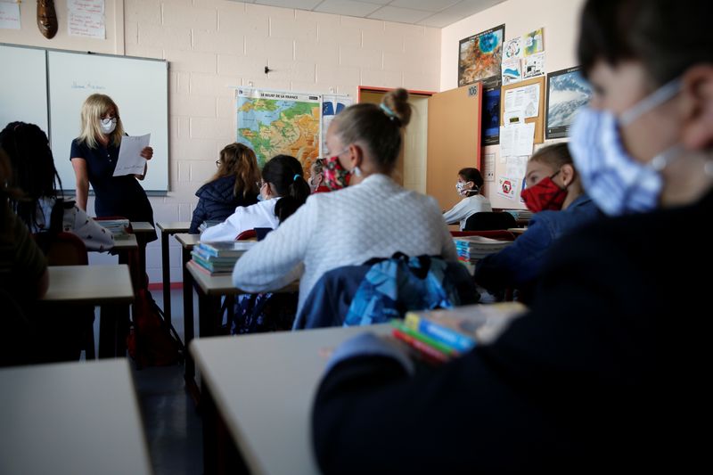 © Reuters. French children resume school after summer break in Saint-Un insegnante, che indossa una maschera protettiva, parla agli studenti in un'aula della scuola College Jules Valles durante la sua riapertura a Saint-Leu-d'Esserent, in Francia