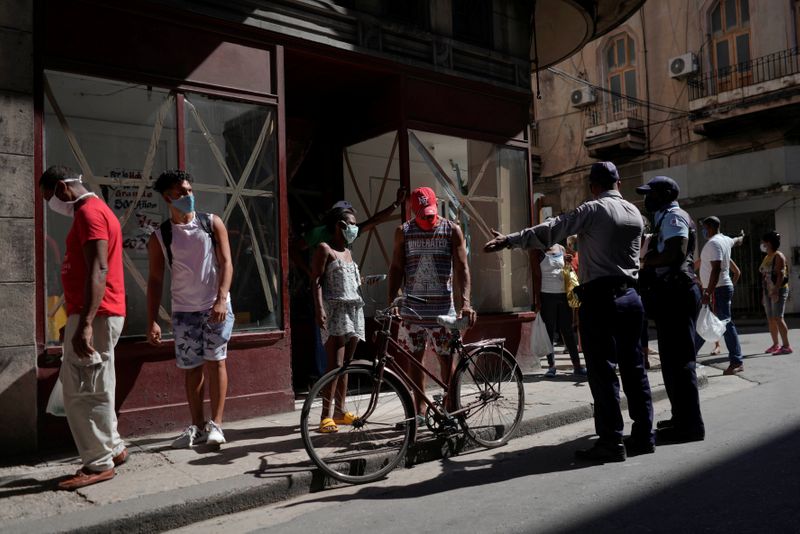 &copy; Reuters. Policial organiza fila de pessoas para comprar comida em Havana