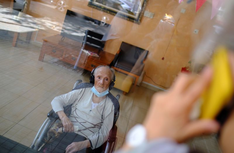 © Reuters. Elderly people get love through nursing home glass front as COVID-19 surges