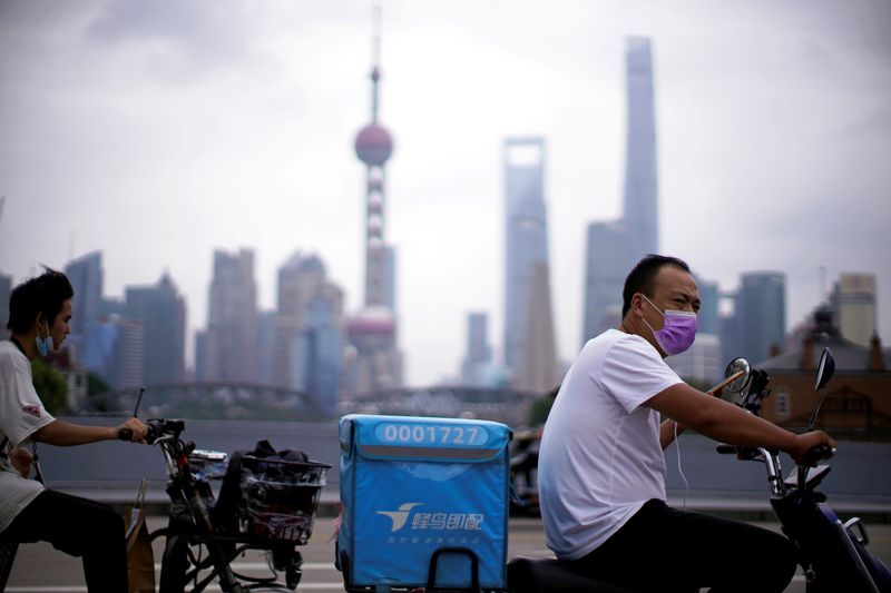 &copy; Reuters. FILE PHOTO: Delivery workers wearing face masks ride scooters in front of Lujiazui financial district, in Shanghai