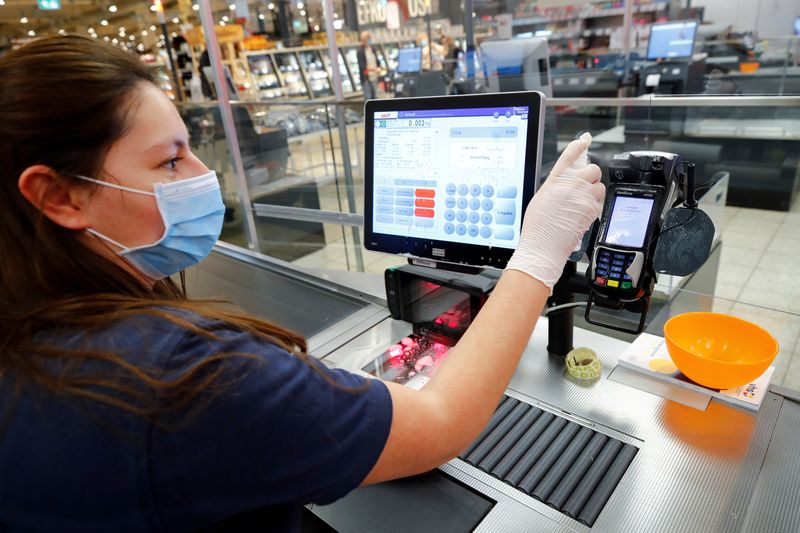 &copy; Reuters. FOTO DE ARCHIVO: Una cajera desinfecta la caja registradora y la terminal de pago de un supermercado cerca de Bonn