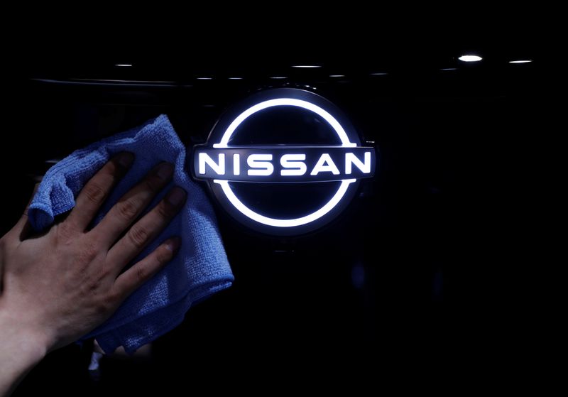 &copy; Reuters. A man wipes the brand logo of Nissan Motor Corp. on the front nose section of the company&apos;s new Ariya all-battery SUV during a press preview in Yokohama