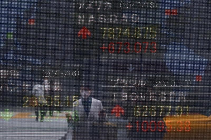&copy; Reuters. A woman wearing a protective face mask, following an outbreak of the coronavirus disease (COVID-19), is reflected in a screen displaying NASDAQ movements outside a brokerage in Tokyo