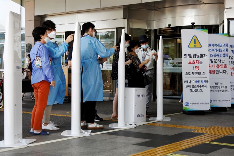 &copy; Reuters. FILE PHOTO: Visitors wearing masks to avoid the spread of COVID-19 fill out a form which is mandatory to get into a hospital in Seoul