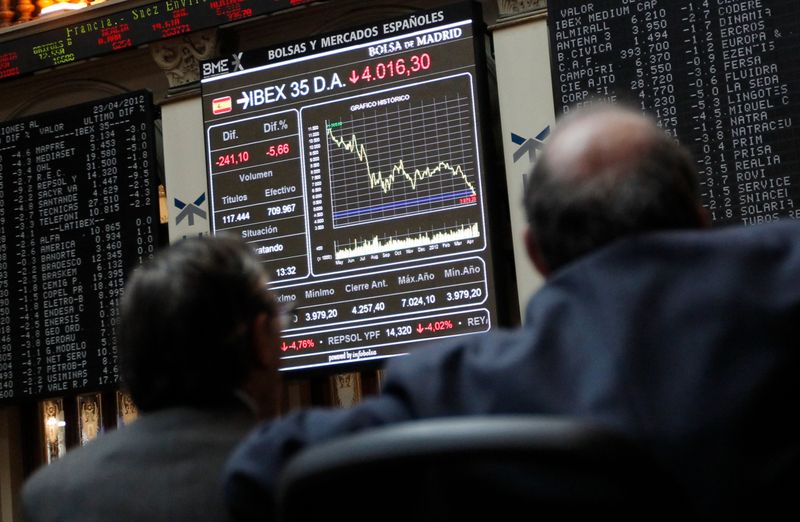 &copy; Reuters. FOTO DE ARCHIVO. Operadores bursátiles miran un tablero con el movimiento del IBEX 35, en Madrid, España