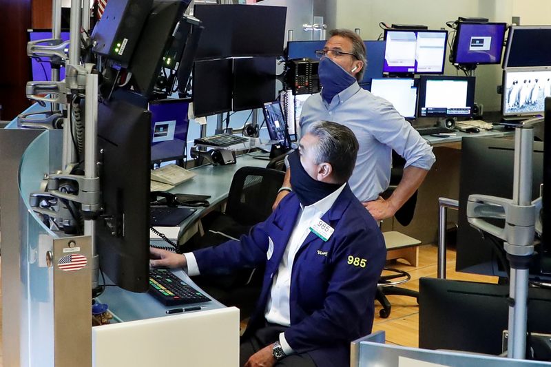 © Reuters. Traders wearing masks work, on the first day of in-person trading since the closure during the outbreak of the coronavirus disease (COVID-19) on the floor at the NYSE in New York