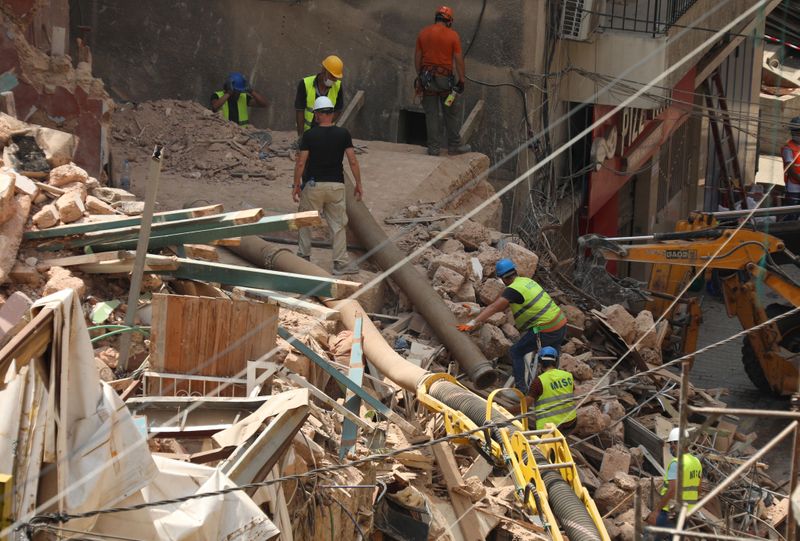 &copy; Reuters. Voluntarios y un miembro del equipo de rescate chileno excavan entre los escombros de edificios que colapsaron debido a la explosión en el área del puerto, luego de que se detectaran señales de vida, en Gemmayze, Beirut, Líbano