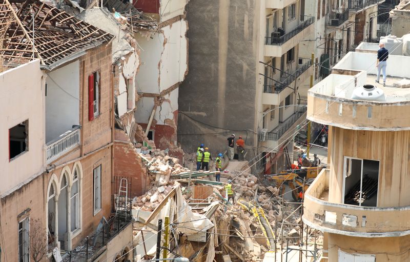© Reuters. Voluntarios y un miembro del equipo de rescate chileno excavan entre los escombros de edificios que colapsaron debido a la explosión en el área del puerto, luego de que se detectaran señales de vida, en Gemmayze, Beirut, Líbano