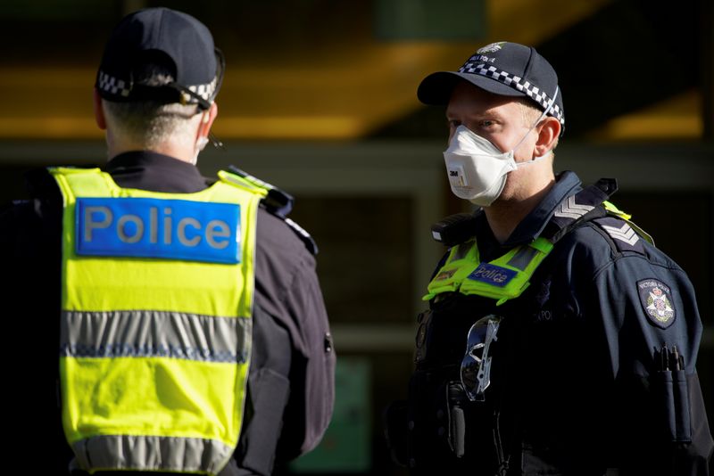 &copy; Reuters. Police meet outside a public housing tower, locked down in response to a COVID-19 outbreak, in Melbourne