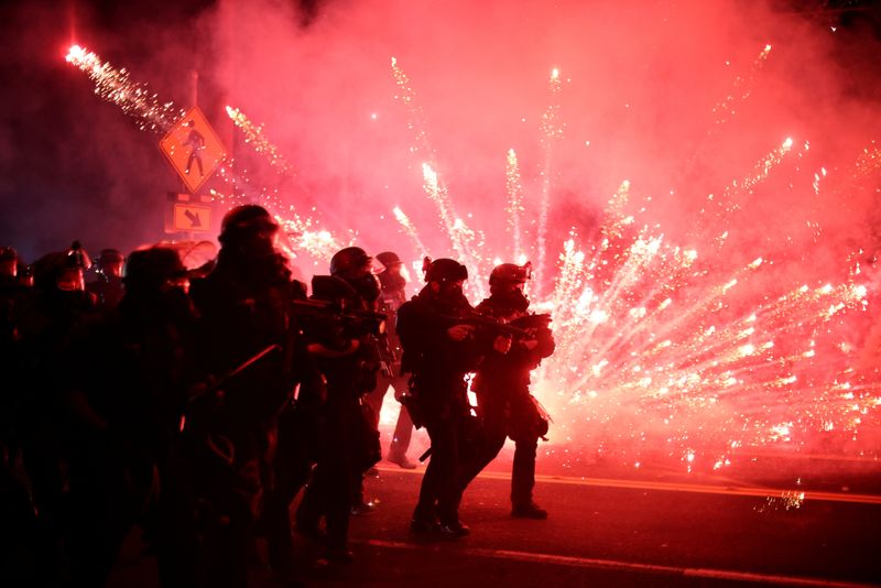 © Reuters. Police advance on protesters to clear a street on the 100th consecutive night of protests against police violence and racial inequality, in Portland, Oregon