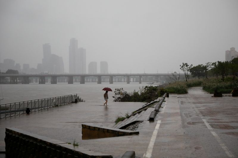 &copy; Reuters. A woman takes a walk as it rains amid the coronavirus disease (COVID-19) pandemic at a Han River park in Seoul