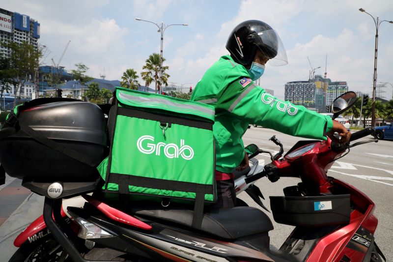 &copy; Reuters. FILE PHOTO: A GrabFood rider gets ready for a delivery outside a shopping mall, amid the coronavirus disease (COVID-19) outbreak in Kuala Lumpur