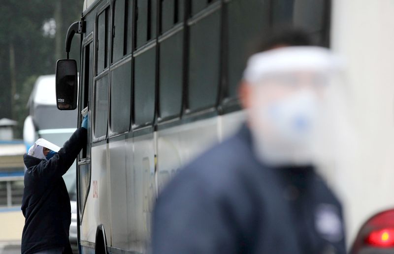 © Reuters. A JBS SA poultry factory employee checks a bus driver's temperature after the company was hit by an outbreak of coronavirus disease (COVID-19) in Passo Fundo