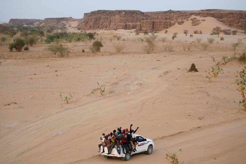 &copy; Reuters. FILE PHOTO: Migrants crossing the Sahara desert into Libya ride on the back of a pickup truck outside Agadez