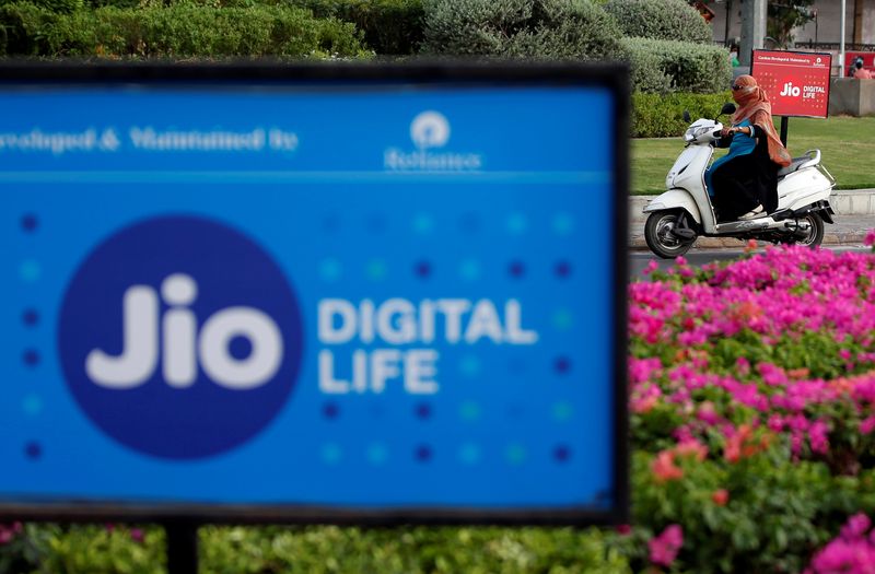 &copy; Reuters. A woman rides her scooter past advertisements of Reliance Industries&apos; Jio telecoms unit, in Ahmedabad