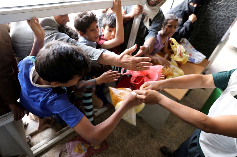 &copy; Reuters. FILE PHOTO: People crowd to get food rations from a charity kitchen in Sanaa