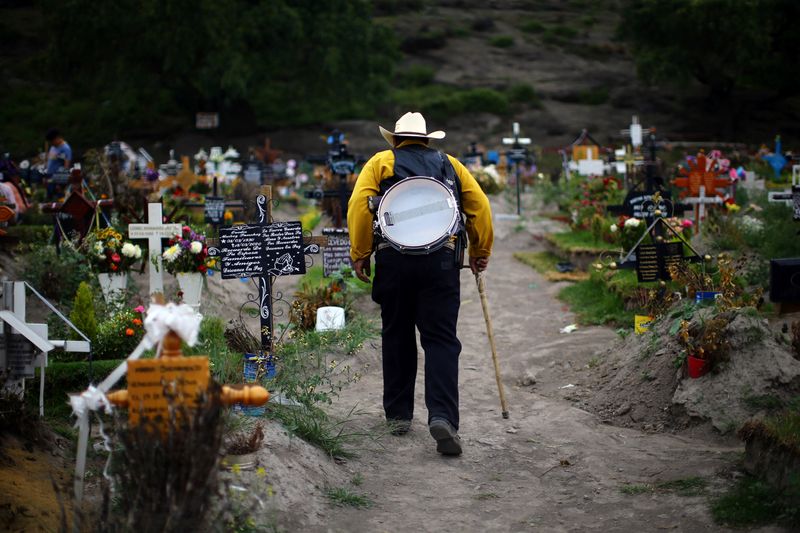 &copy; Reuters. Músico caminha entre túmulos em cemitério em Valle de Chalco, no Estado do México