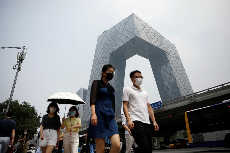 &copy; Reuters. People wearing face masks walk past the CCTV headquarters in Beijing