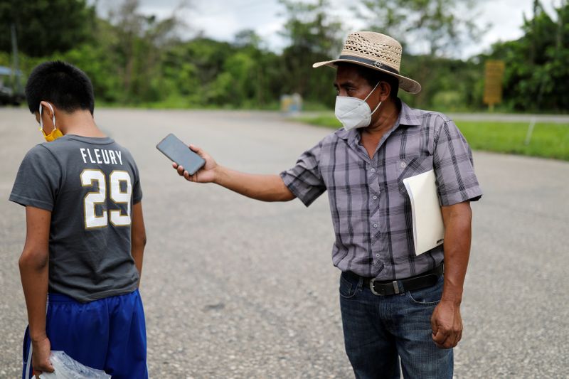 © Reuters. Juan holds his phone with a call from her wife Elida as their disabled 12-year-old son Gustavo walks away to avoid the conversation with her, during their reunion in Peten