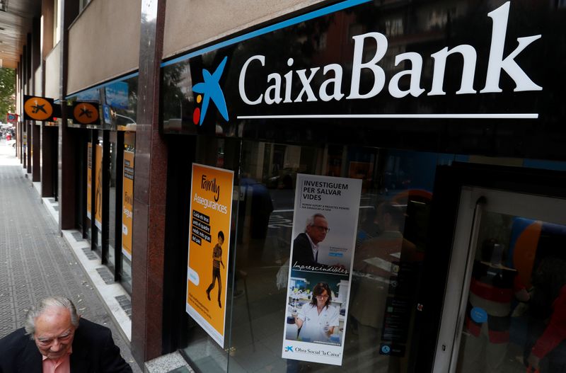 &copy; Reuters. Un uomo passa accanto a una filiale di Caixa bank a Barcellona
