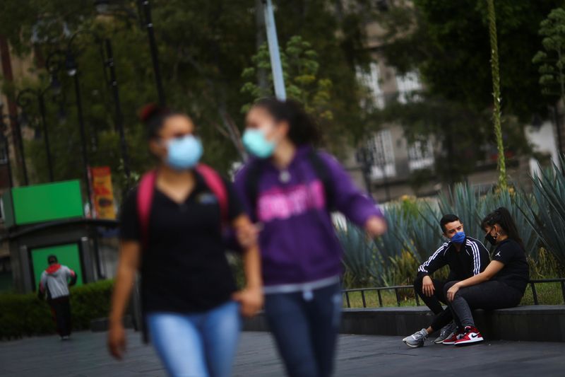 © Reuters. Mexicanos utilizam máscara de proteção enquanto conversam em praça na Cidade do México