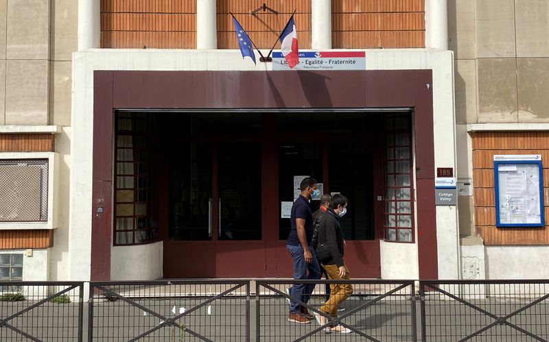 &copy; Reuters. People wearing protective face masks walk past the College Valmy school in Paris