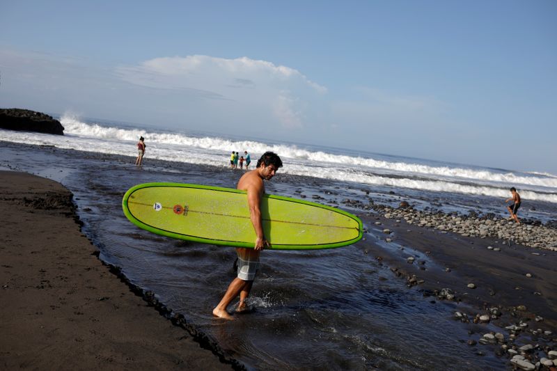 &copy; Reuters. FILE PHOTO: Surfer crosses a stream at El Tunco beach in Tamanique