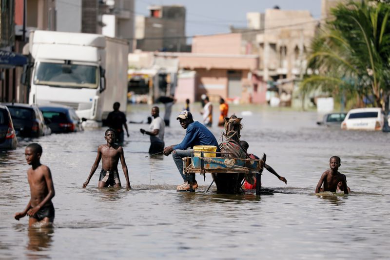 &copy; Reuters. FILE PHOTO: Residents walk through a flooded street after last week&apos;s heavy rains in Keur Massar