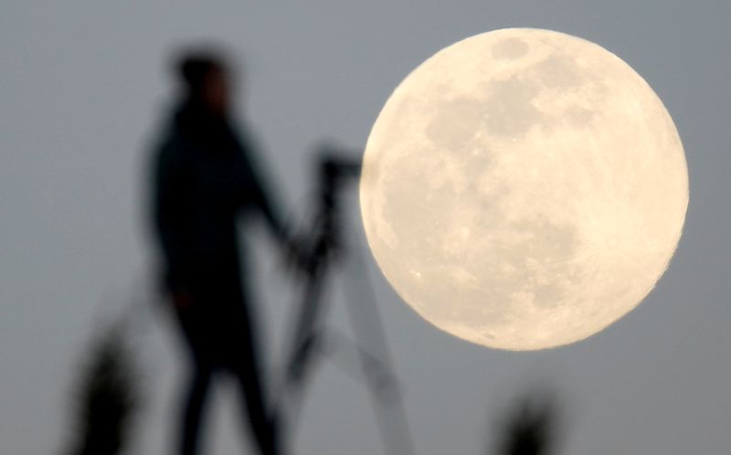 &copy; Reuters. FILE PHOTO: A woman photographs the Pink Supermoon over mountain Smetovi, during an astronomical event that occurs when the moon is closest to the Earth in its orbit, making it appear much larger and brighter than usual, in Zenica