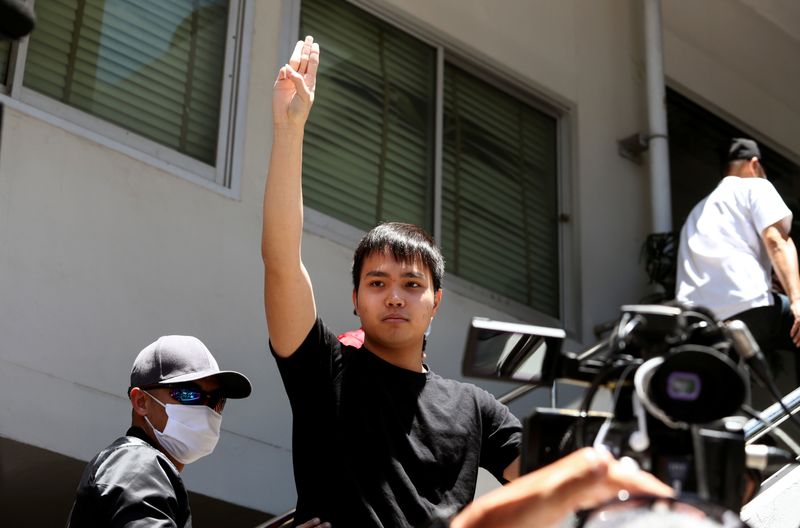 &copy; Reuters. Pro-democracy leader Tattep Ruangprapaikitseree flashes the three-fingers salute as he is escorted by police officers after being arrested, at a police station in Bangkok