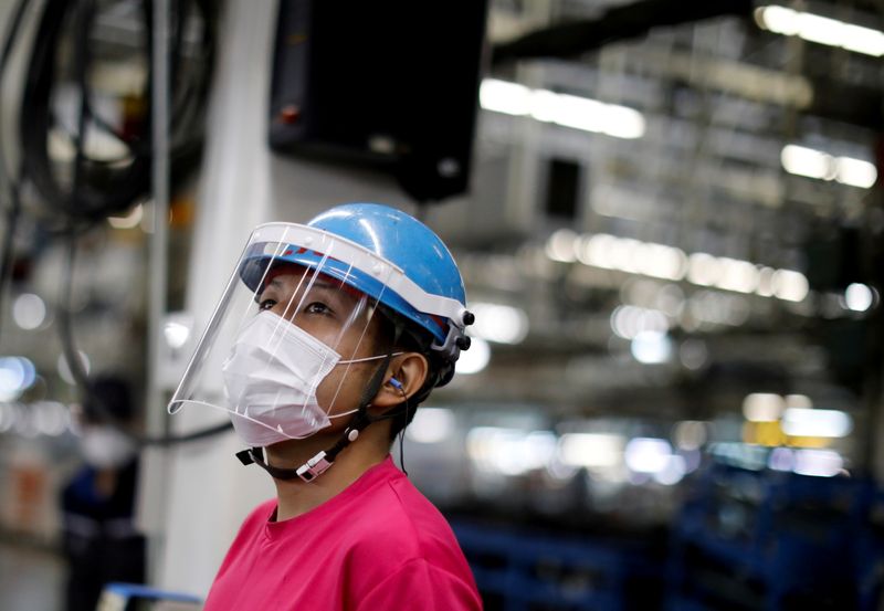 © Reuters. FILE PHOTO: An employee wearing a protective face mask and face guard works on the automobile assembly line during the outbreak of the coronavirus disease (COVID-19) at the factory of Mitsubishi Fuso Truck and Bus Corp. in Kawasaki