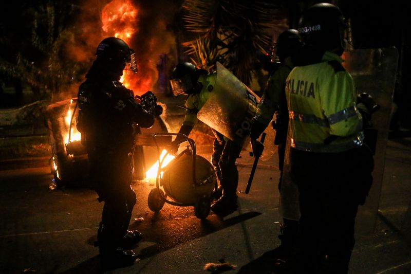 &copy; Reuters. Police officers attempt to extinguish fire from a burning dumpster during a protest after a man, who was detained for violating social distancing rules, died from being repeatedly shocked with a stun gun by officers, according to authorities, in Bogota