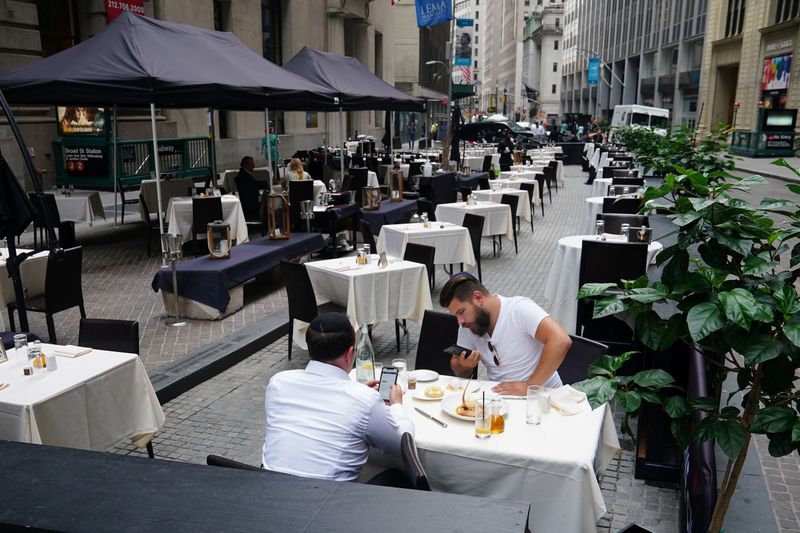 &copy; Reuters. FILE PHOTO: People eat at a mostly empty restaurant with tables on the street in the financial district