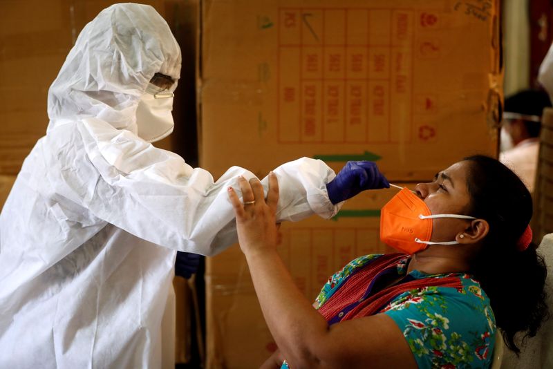 &copy; Reuters. FILE PHOTO: A health worker in personal protective equipment (PPE) collects a swab sample from a woman during a rapid antigen testing campaign for the coronavirus disease (COVID-19), in Mumbai