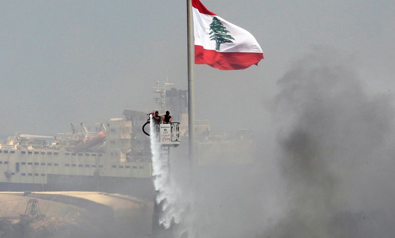 © Reuters. A man uses a water hose to put out the remains of a fire that broke out at Beirut's port yesterday