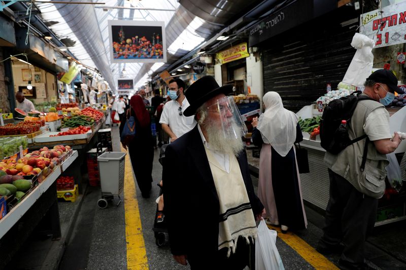 © Reuters. FILE PHOTO: People wear face mask sas they shop in a main market in Jerusalem