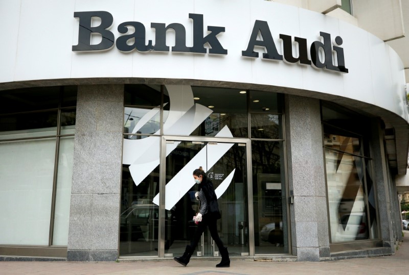 &copy; Reuters. FILE PHOTO: A woman wearing a face mask walks near a closed branch of Bank Audi in Sidon