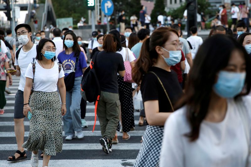 &copy; Reuters. FILE PHOTO: People wearing face masks following the coronavirus disease (COVID-19) outbreak walk across a street at a shopping area in Beijing