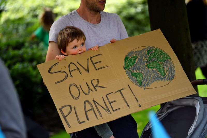 &copy; Reuters. FILE PHOTO: A father and his child are holding a sign as climate activists protest in London