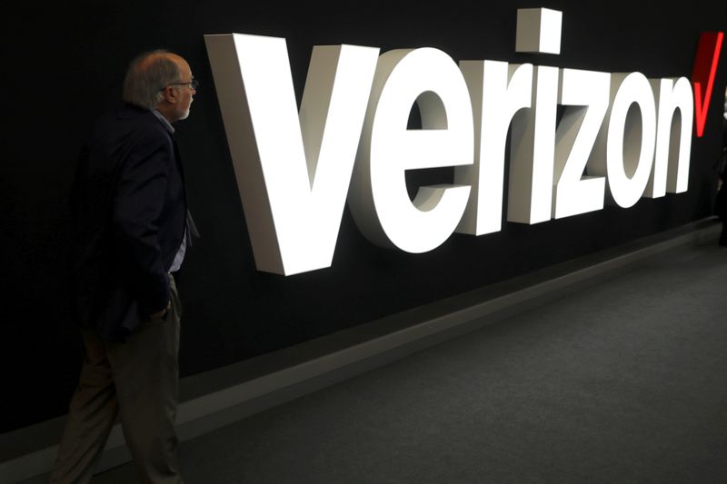 © Reuters. FILE PHOTO: A man stands next to the logo of Verizon at the Mobile World Congress in Barcelona