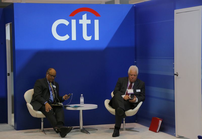 &copy; Reuters. Two men look at their mobile phones under the Citigroup logo at the SIBOS banking and financial conference in Toronto