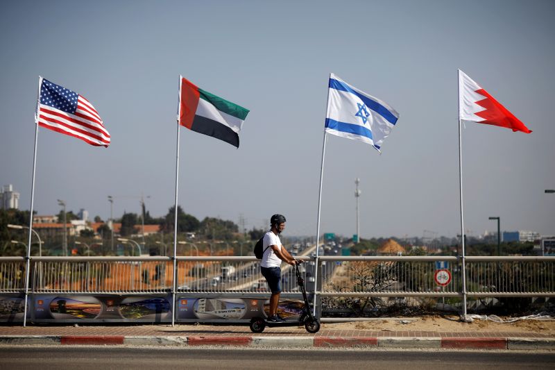 &copy; Reuters. A man rides a scooter near the flags of the U.S., United Arab Emirates, Israel and Bahrain as they flutter along a road in Netanya