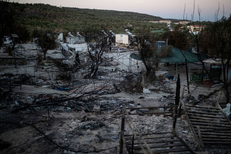 © Reuters. FILE PHOTO: Men make their way at the destroyed Moria camp for refugees and migrants, on the island of Lesbos