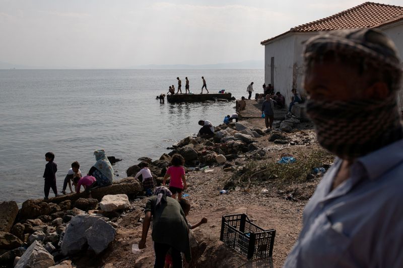 &copy; Reuters. Refugees and migrants from the destroyed Moria camp are seen on a beach near a new temporary camp, on the island of Lesbos