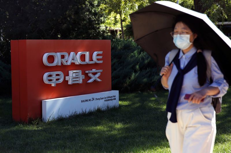 © Reuters. Pedestrian wearing a face mask following the COVID-19 outbreak walks past a sign of Oracle in front of its office buildings in Beijing