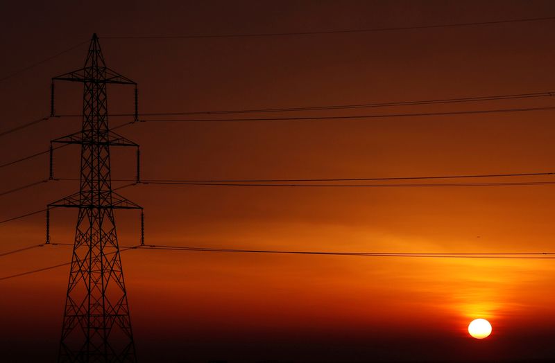&copy; Reuters. FILE PHOTO: The sun is seen behind high-voltage power lines and electricity pylons at a highway northeast of Cairo