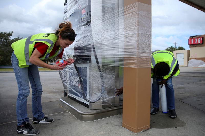 © Reuters. FILE PHOTO: Gas station attendants wrap pumps in plastic as Hurricane Sally approaches to Pass Christian