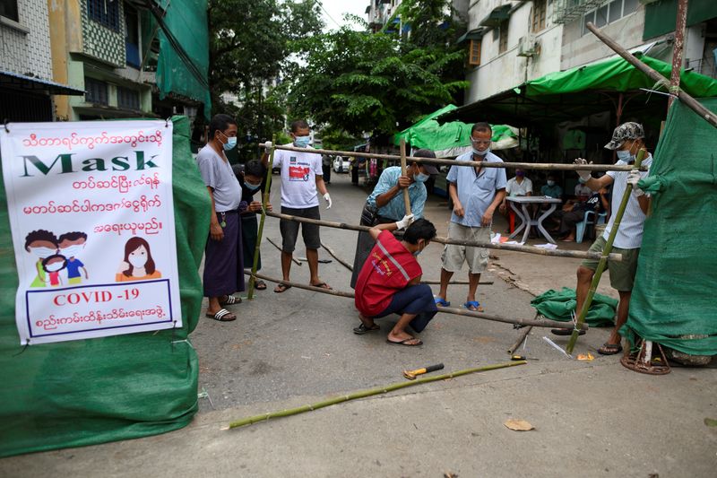 &copy; Reuters. Men construct a barricade blocking off their street to prevent the spread of the coronavirus disease in Yangon