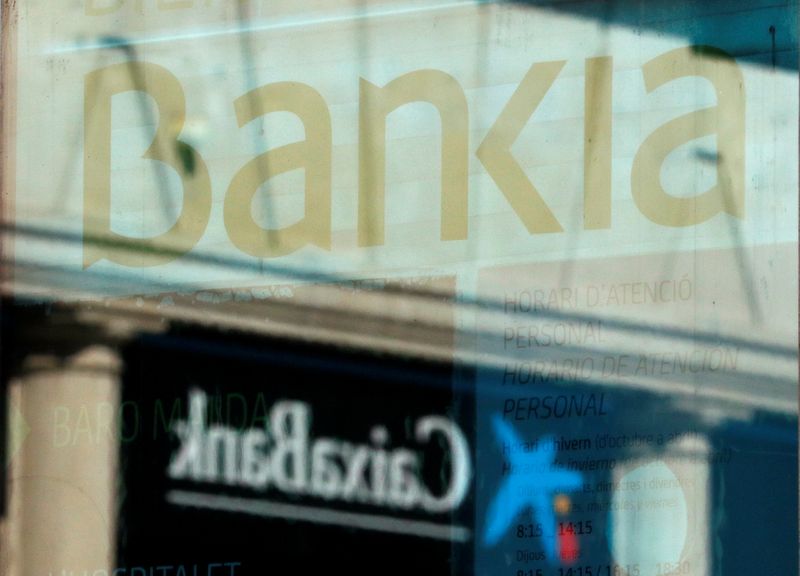 &copy; Reuters. Loghi di Caixabank e Bankia riflessi sulle vetrate degli uffici dei due istituti di credito, nei pressi di Barcellona