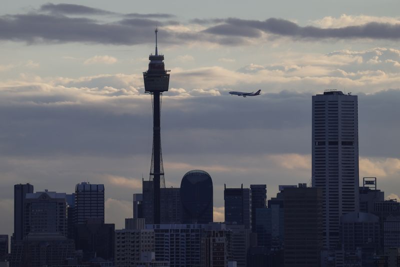 © Reuters. A Qantas plane flies over the city centre skyline in Sydney